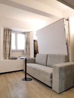 A modern living room with a sofa, a small side table, and a window with curtains.