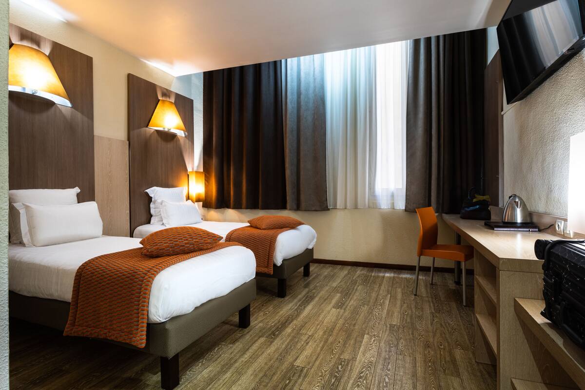 Ein Hotelzimmer mit zwei Betten, einem Schreibtisch und einem Stuhl.