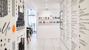 A hallway with tiled flooring, a wall with black and white patterns, and a door leading to another room.