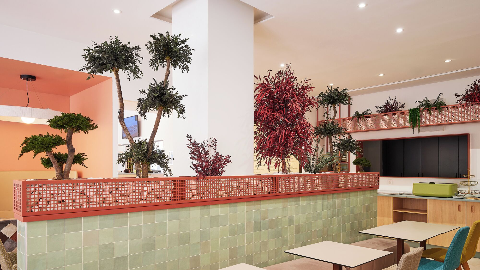 A modern interior with a dining area, a TV mounted on the wall, and various potted plants.