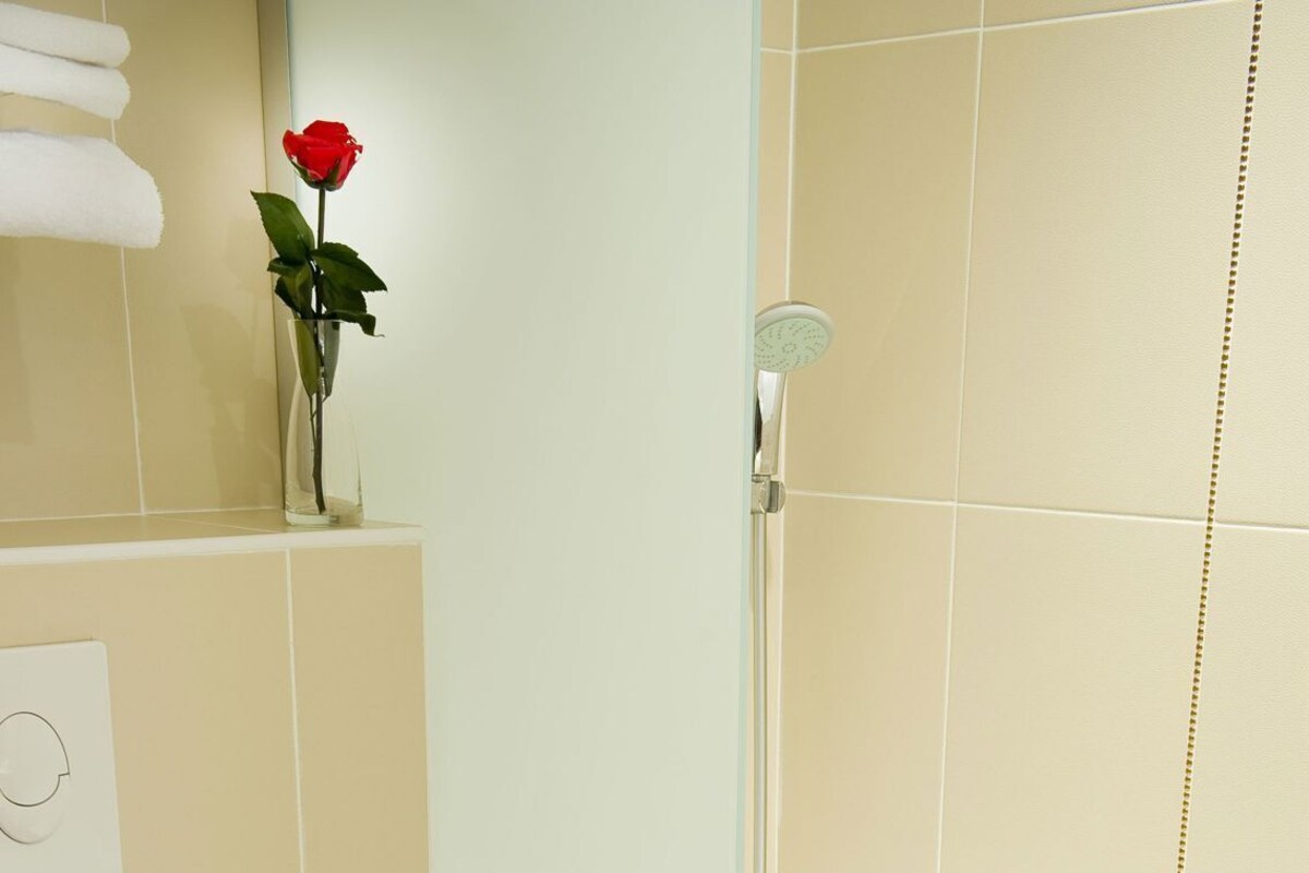 Une salle de bain avec une baignoire blanche, une douche, des toilettes et un porte-serviettes.