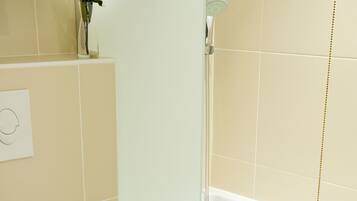 Un baño con inodoro blanco, cabina de ducha de vidrio y bañera.