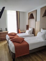 Habitación de hotel con dos camas, un escritorio, una silla y una lámpara.