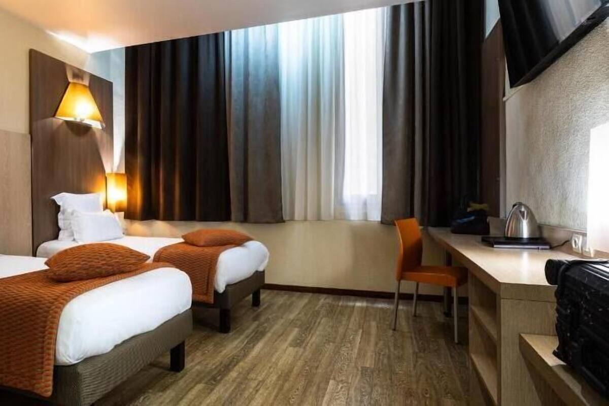 Une chambre d’hôtel avec deux lits, un bureau et une chaise.