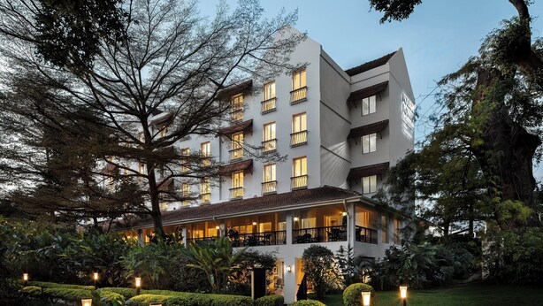 Un hotel de varios pisos con balcones, un jardín bien cuidado e iluminación exterior.