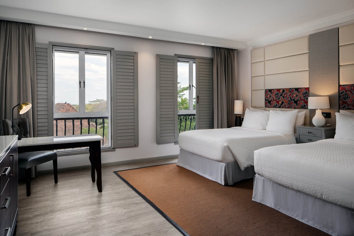 Ein Hotelzimmer mit zwei Betten, einem Schreibtisch und Blick ins Freie.