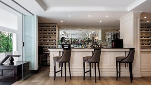 Un área de bar con tres taburetes, una botellera y un espejo grande.