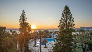 A resort with a pool, lounge chairs, and a view of the sunset over the ocean. - Marhaba Beach (Sousse)