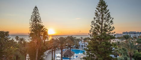 Un resort con piscina, sillones de descanso y vistas al atardecer sobre el océano.