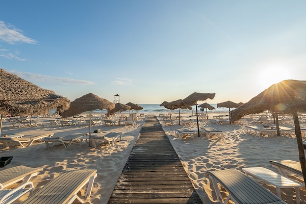 Praia particular, areia branca, espreguiçadeiras, guarda-sóis