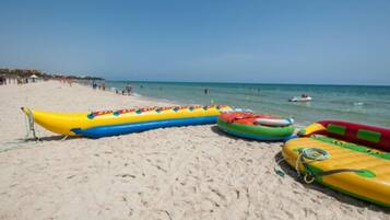 A beach with inflatable rafts and a clear sky.