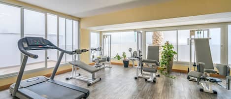 A gym with a treadmill, weight machines, and exercise chairs.