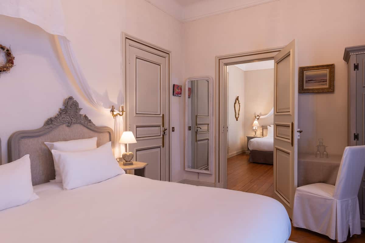 Habitación de hotel con una cama grande, una mesita de noche con lámpara, una silla y un armario.