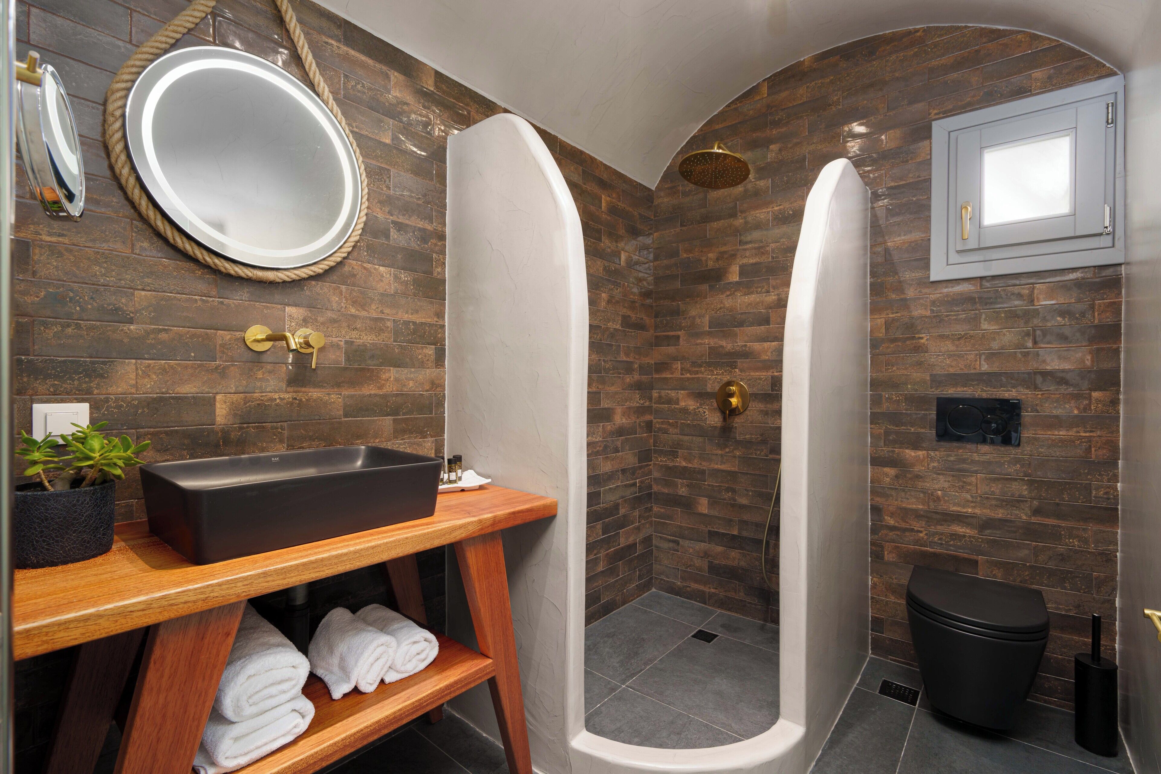 Ein modernes Badezimmer mit einem Holzlager, einem großen Spiegel, einem schwarzen Waschbecken und einer Duschkabine.