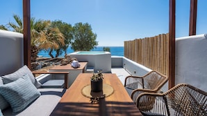 A rooftop terrace with a wooden pergola, a pool, and a view of the sea.