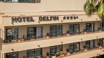 A hotel with a sign reading 'HOTEL DELFIN' and balconies with outdoor seating.