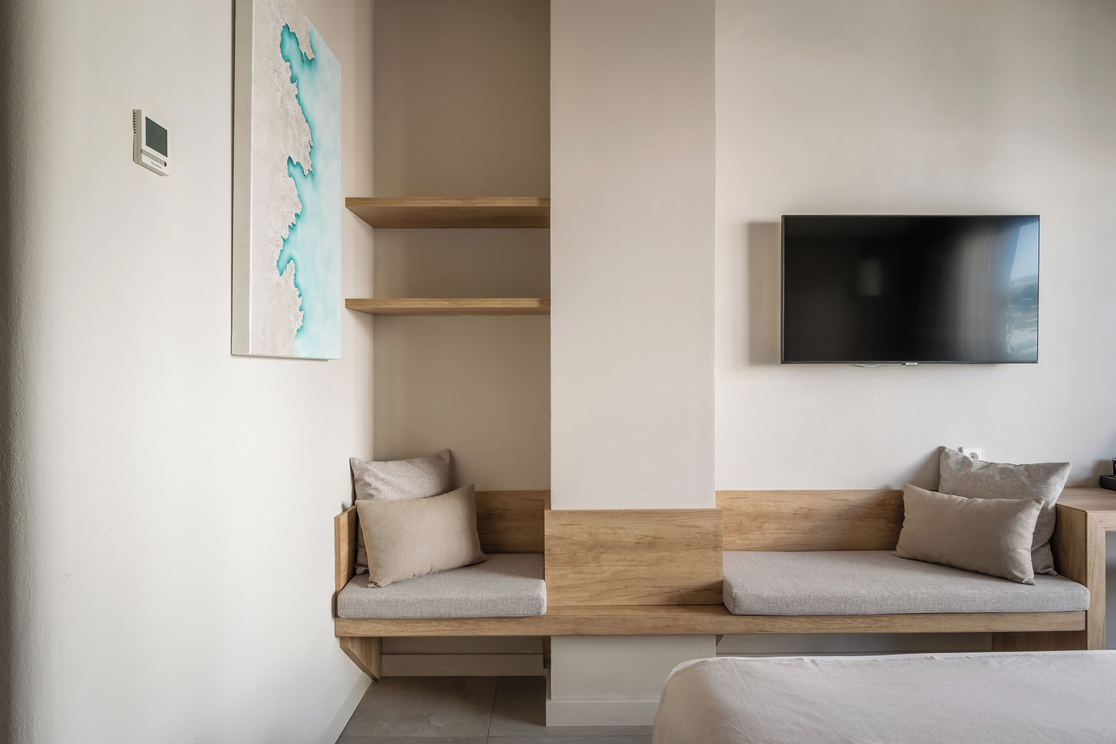 Una habitación moderna con un banco empotrado, un televisor de pantalla plana y una estantería fijada a la pared.