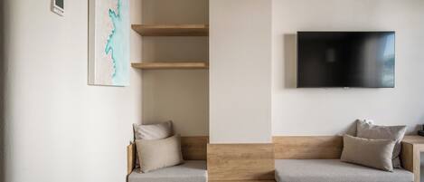 Una habitación moderna con un banco empotrado, un televisor de pantalla plana y una estantería fijada a la pared.