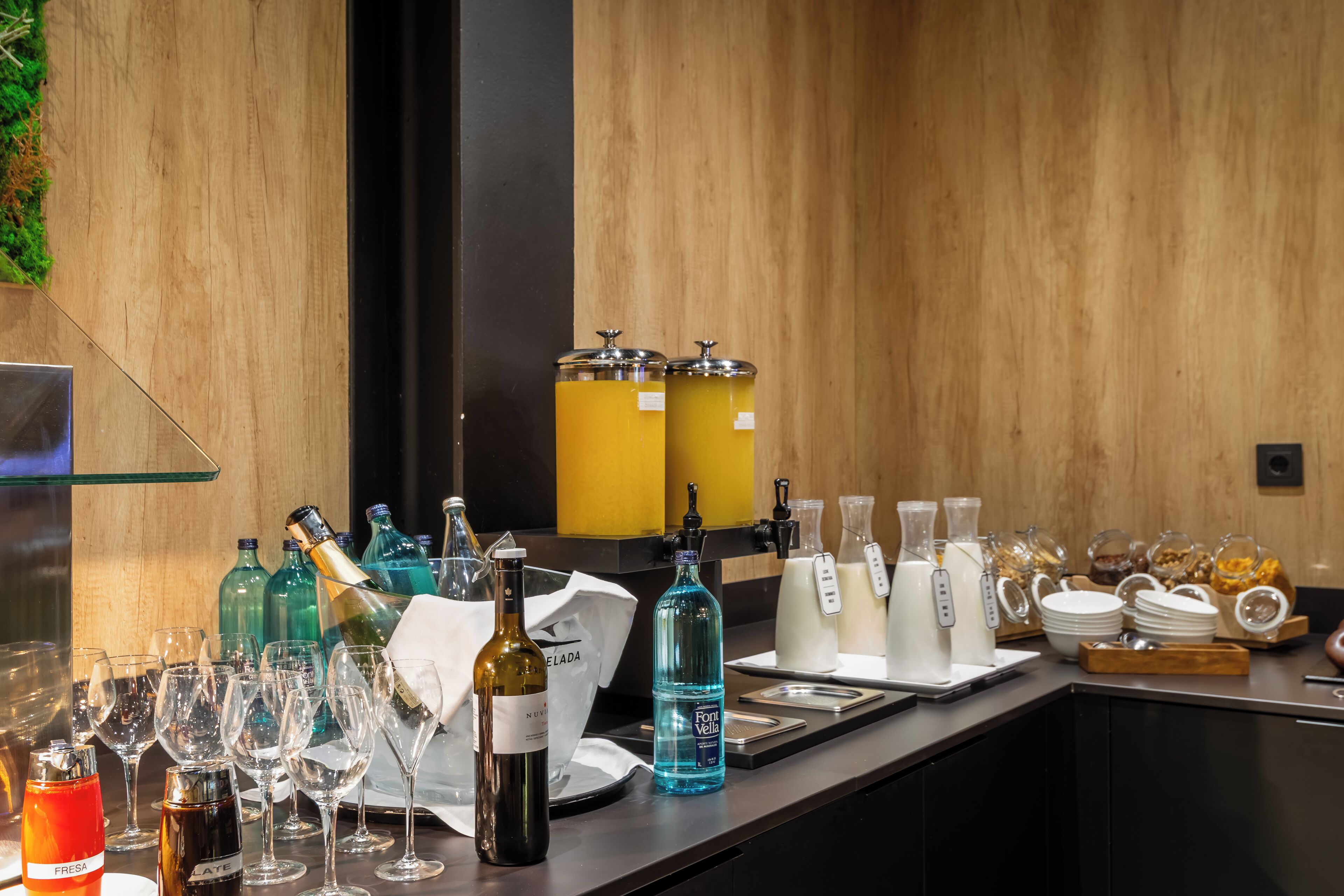 Een bar met wijnflessen, glazen en een waterdispenser.