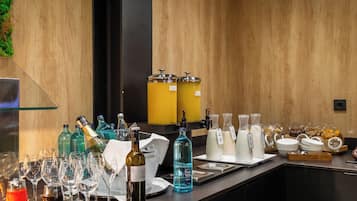 Zona de bar con botellas de vino, vasos y dispensador de agua.