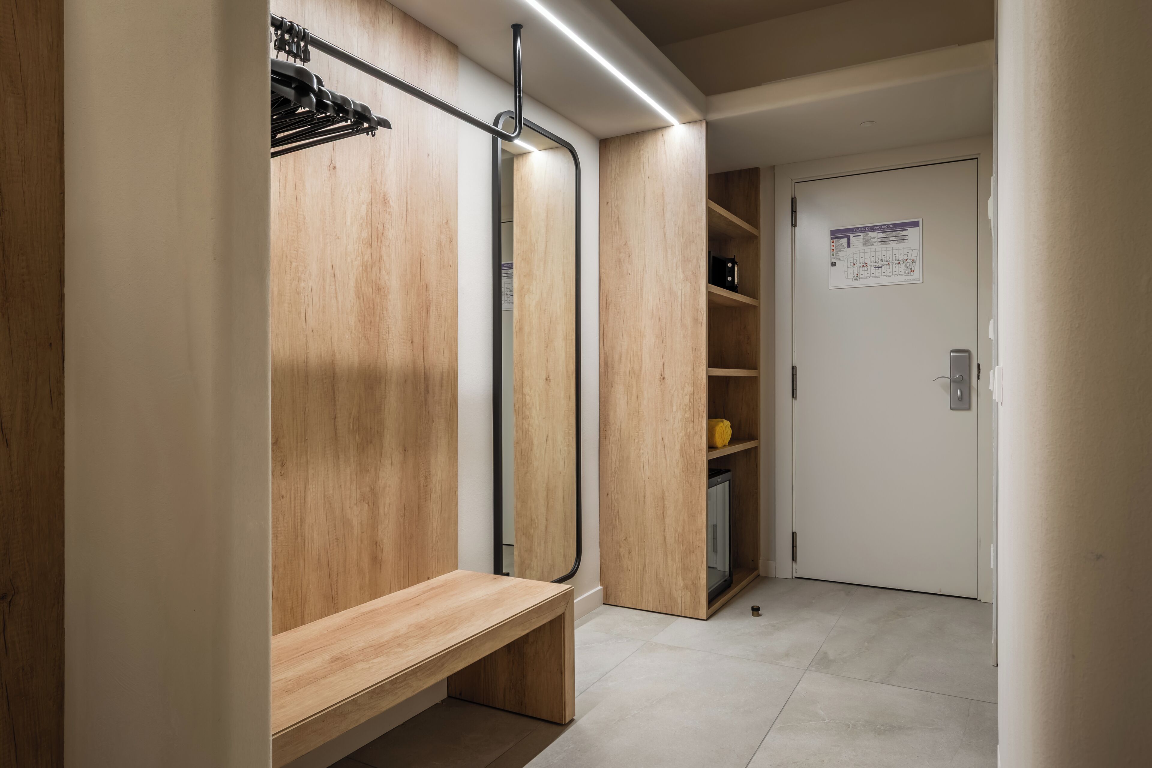 Un baño moderno con un banco de madera, un espejo y una zona de ducha.
