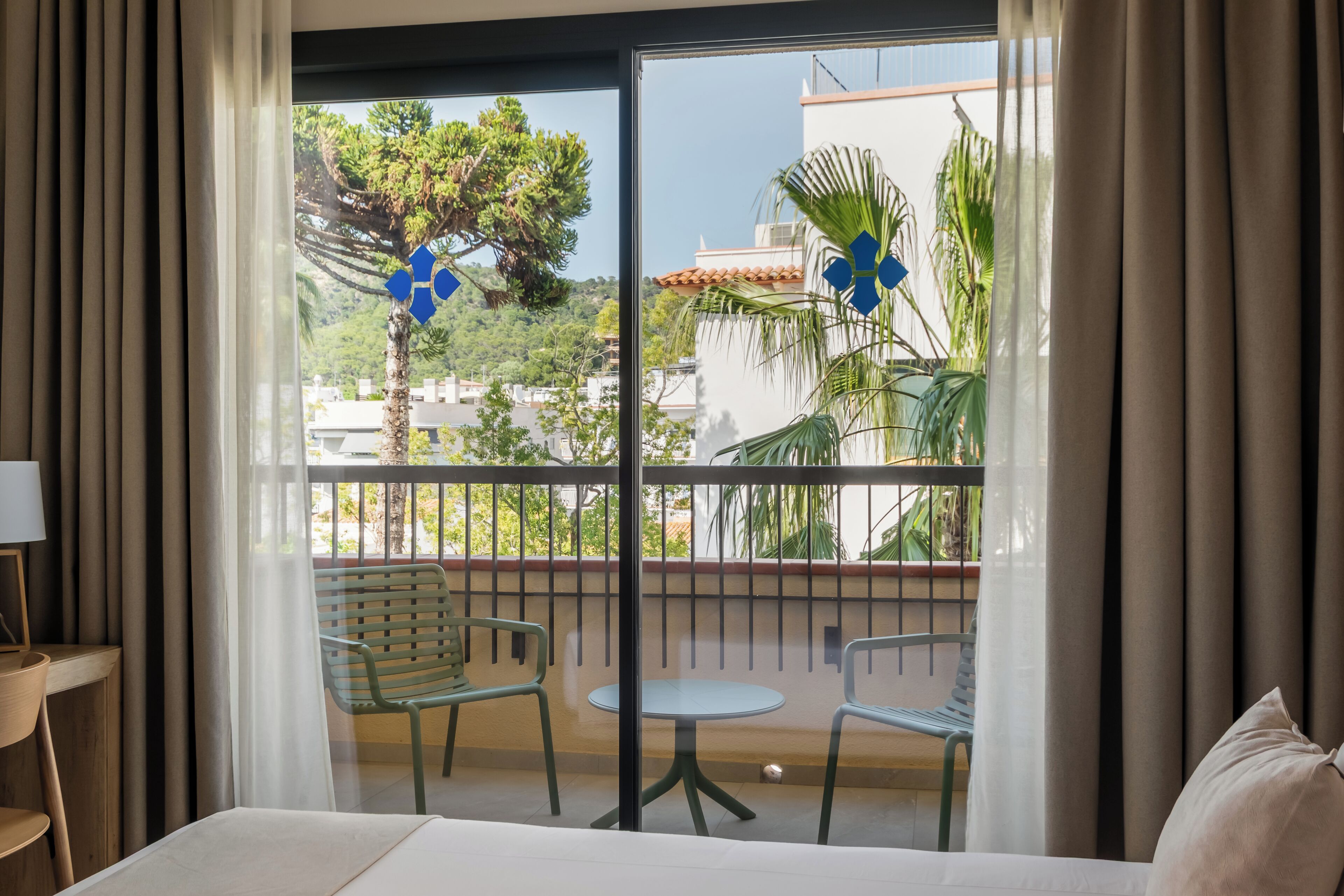Una habitación de hotel con balcón, cama, silla y mesa.