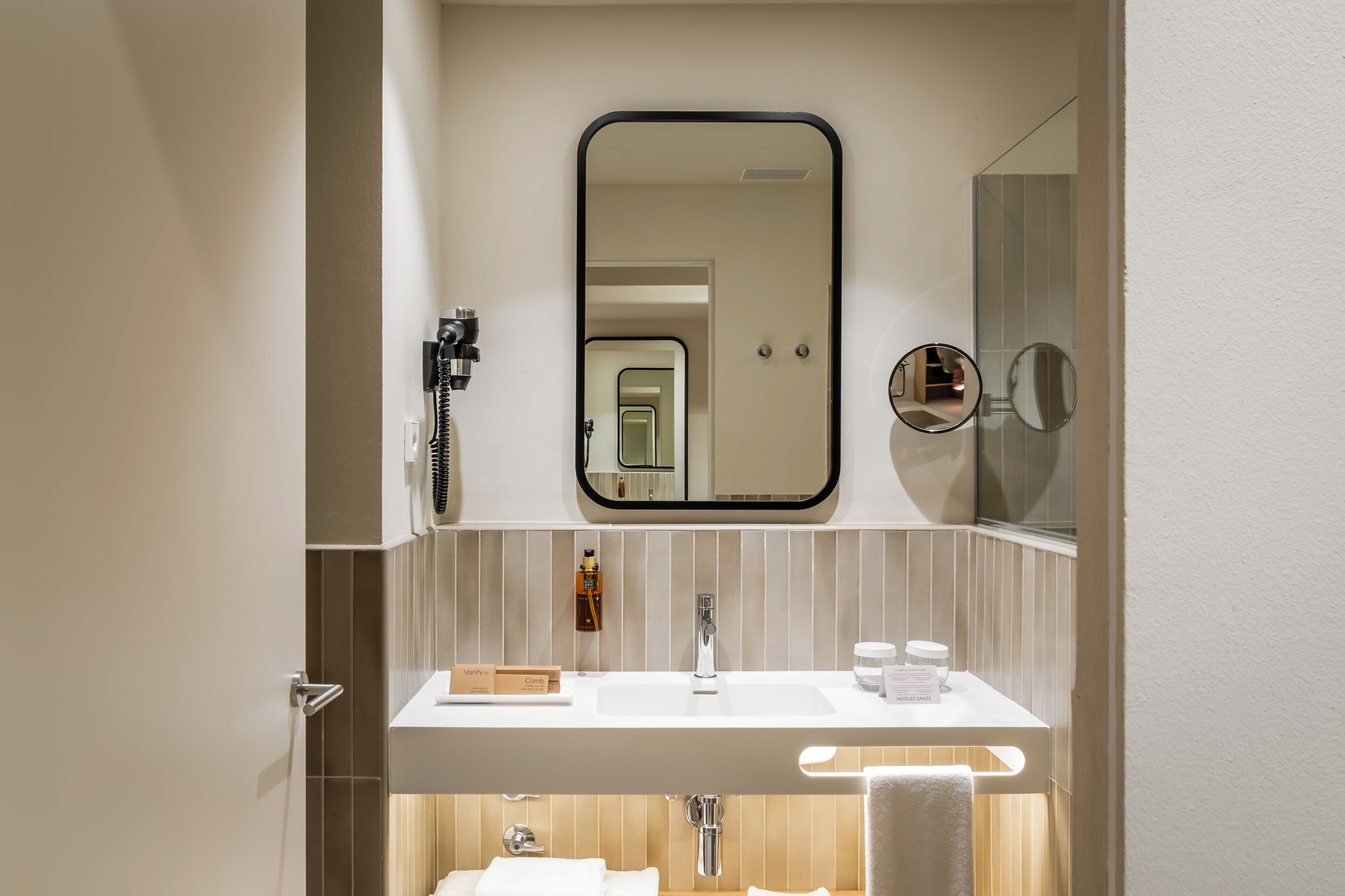 A bathroom with a large mirror, a sink, and a towel rack.