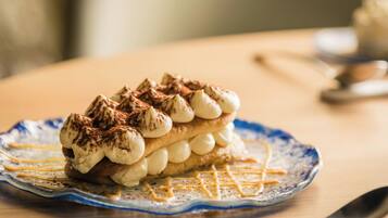 Een dessert op een bord, met een lepel en een kom op de achtergrond.