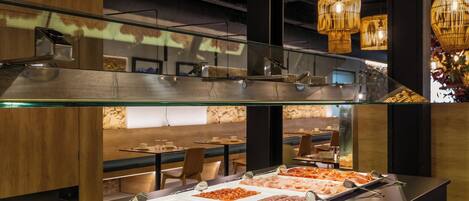 A buffet area with multiple food stations and a glass railing overlooking a dining area.