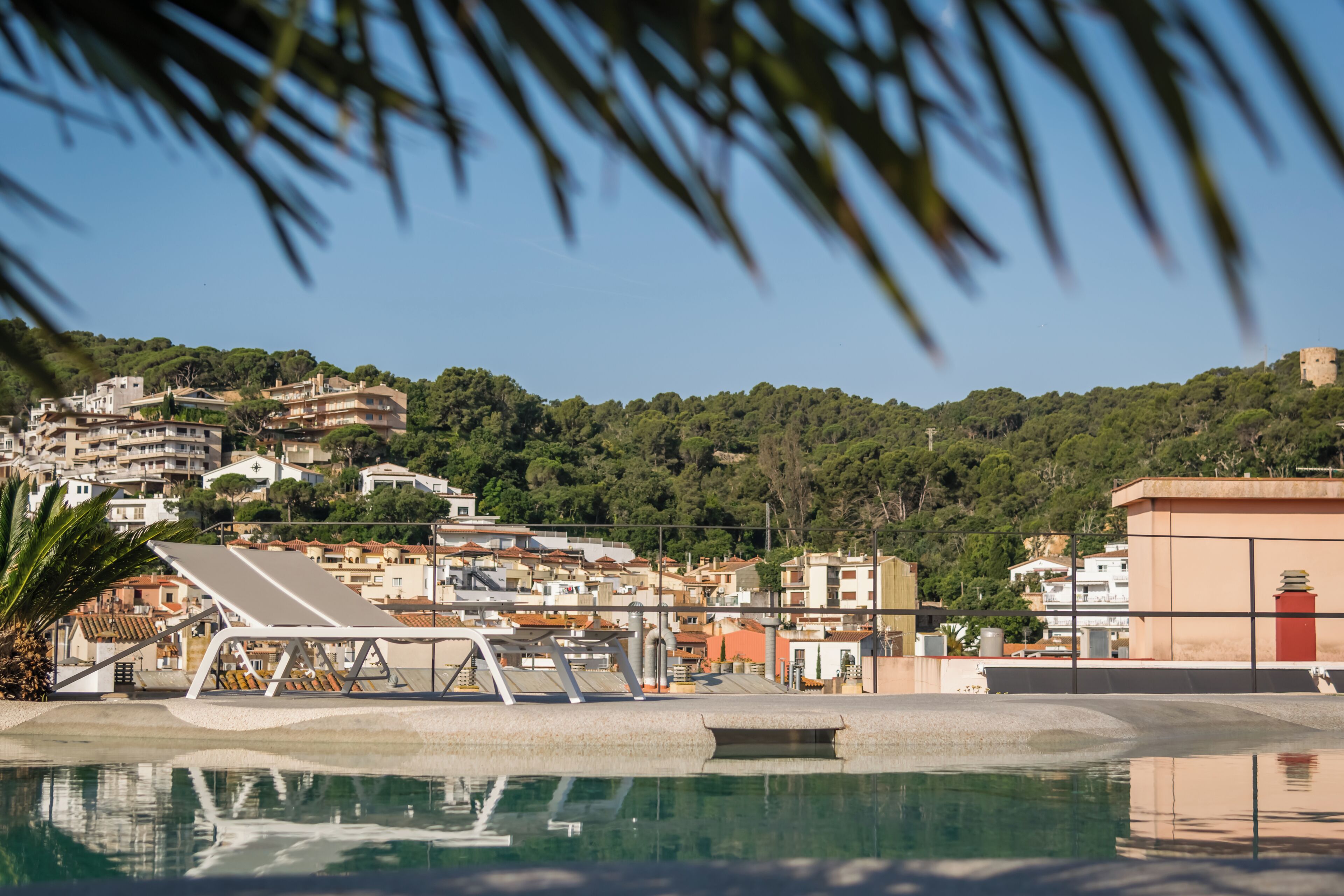 A pool area with a clear view of surrounding buildings and a hill in the background.