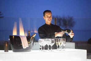 Iemand schenkt champagne in glazen aan een tafel, met een grote emmer en een fles.