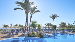 Un espace piscine avec des chaises longues et des palmiers.