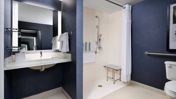 A modern bathroom with a large mirror, a sink, a shower, and a toilet.