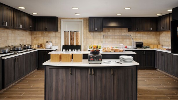Een moderne keuken met donkerhouten kasten, een centraal eiland en diverse apparaten.