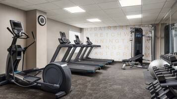 A gym with treadmills, elliptical machines, and weight benches.