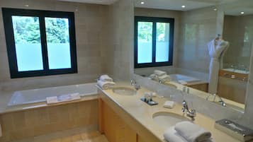 A modern bathroom with a bathtub, two sinks, and a large mirror.