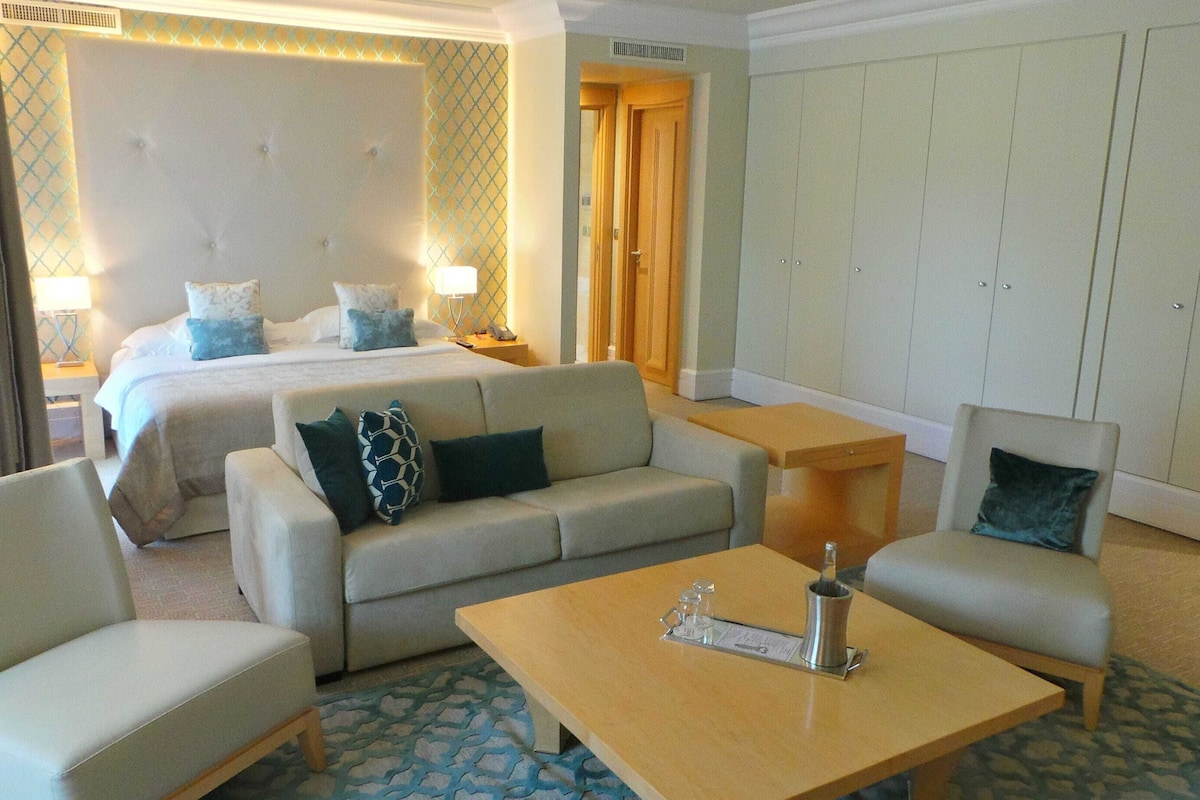 A hotel room with a bed, a sofa, a coffee table, and a wardrobe.