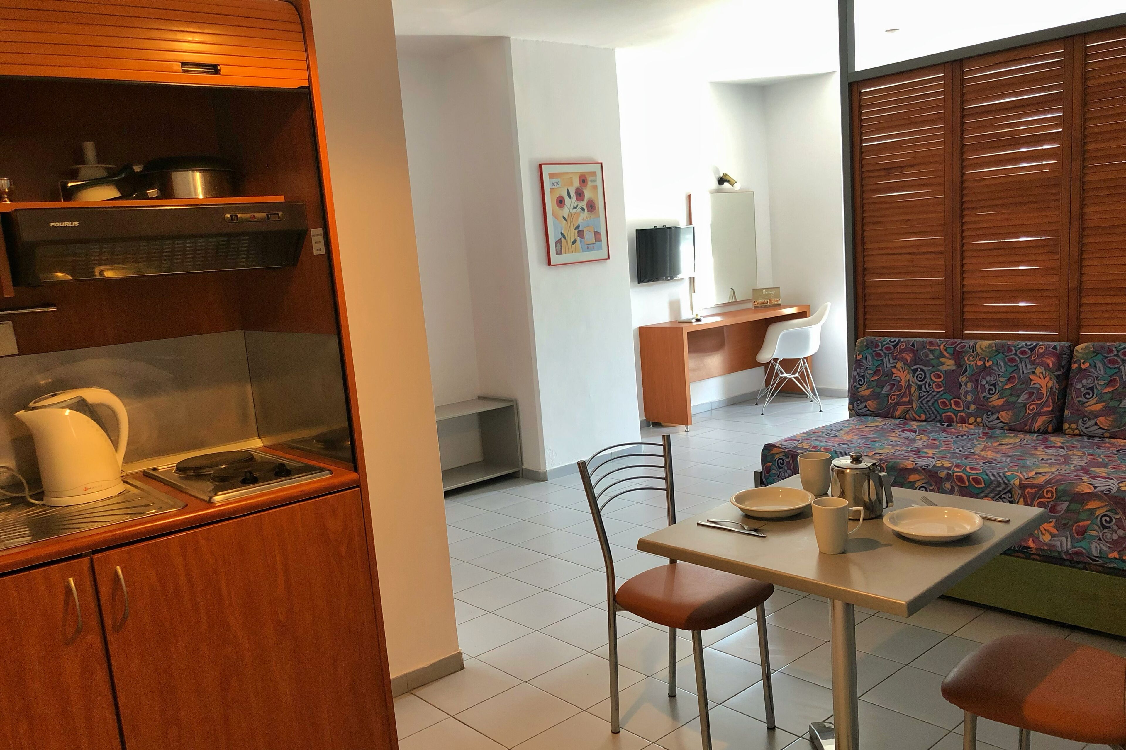 A compact living space with a kitchenette, a dining area, and a sofa.