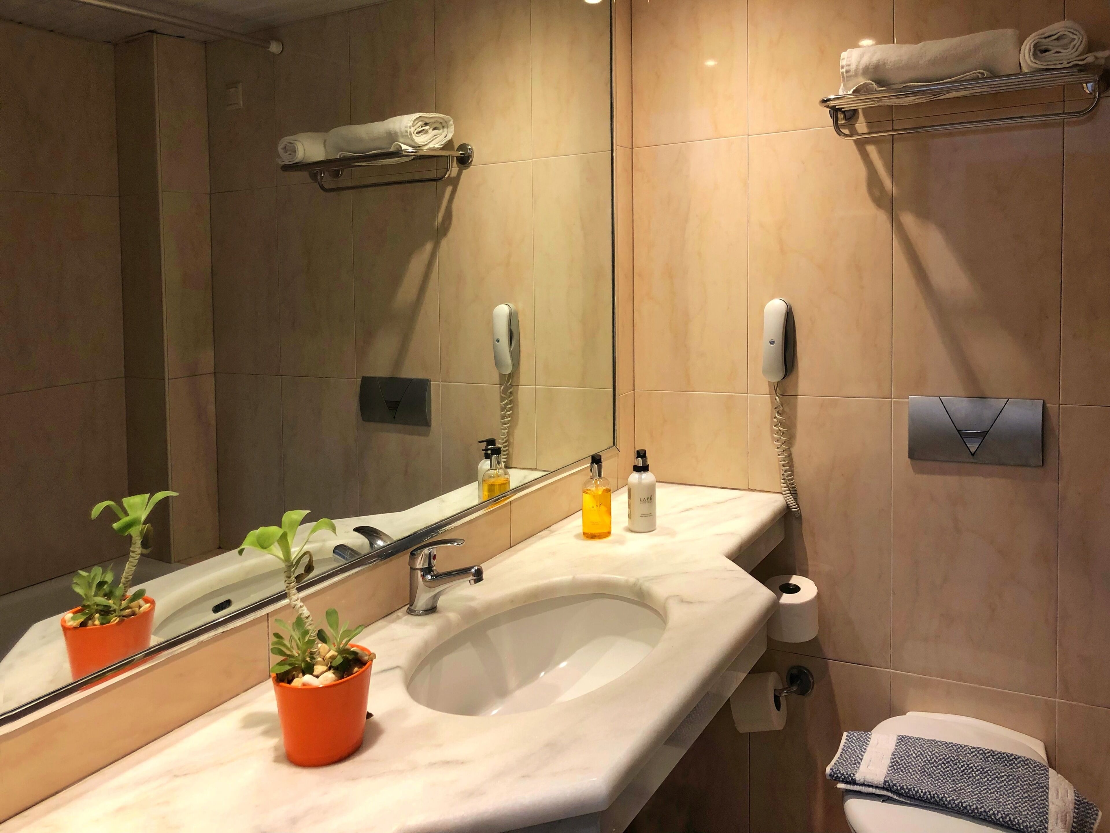 Un baño moderno con lavamanos, espejo, toallero y retrete.