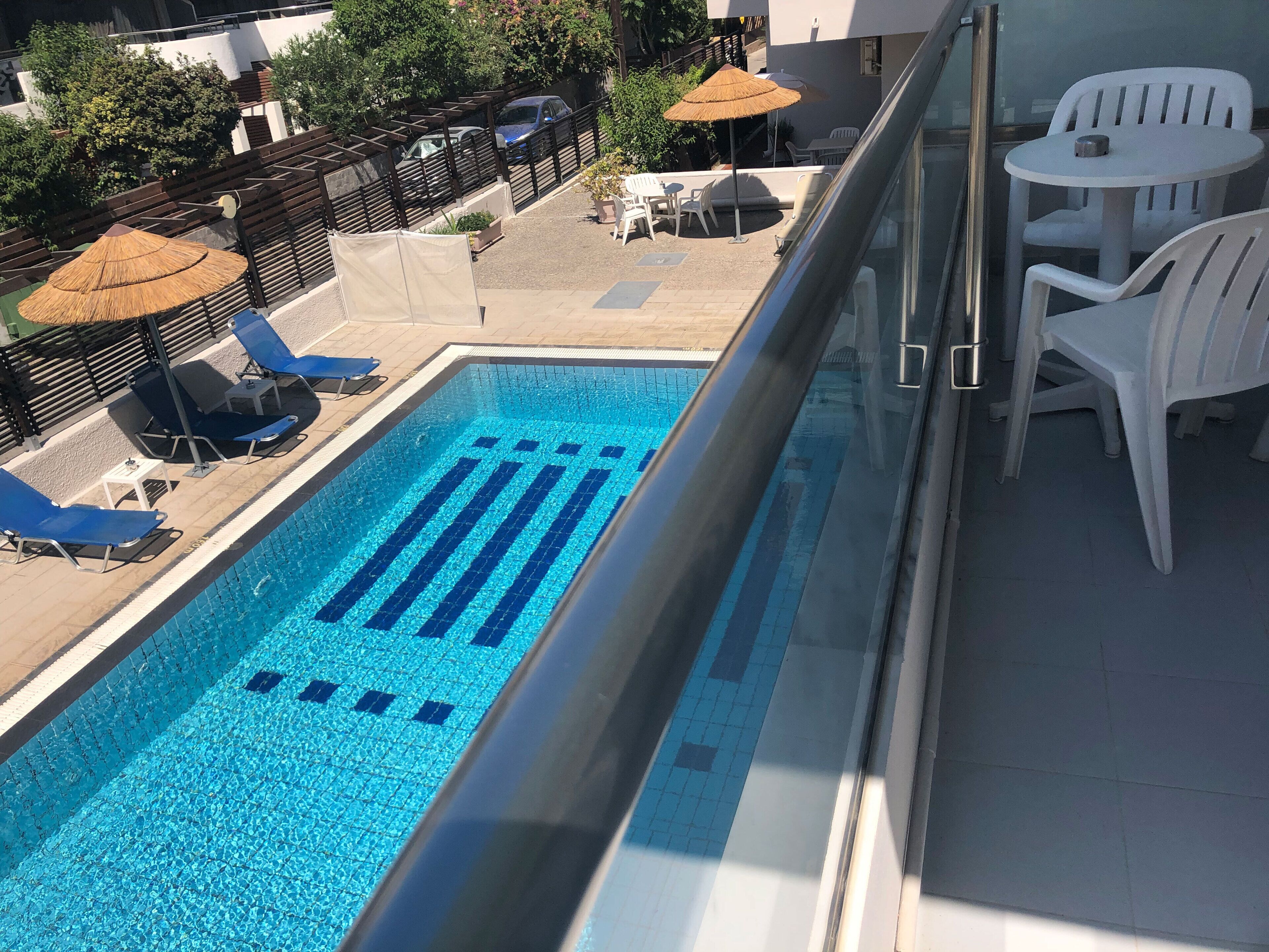 Une piscine sur le toit, avec des carreaux bleus, des chaises longues et des parasols.
