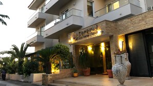 Un hôtel à plusieurs étages, doté d’une façade en pierre, de balcons et de plantes en pot.