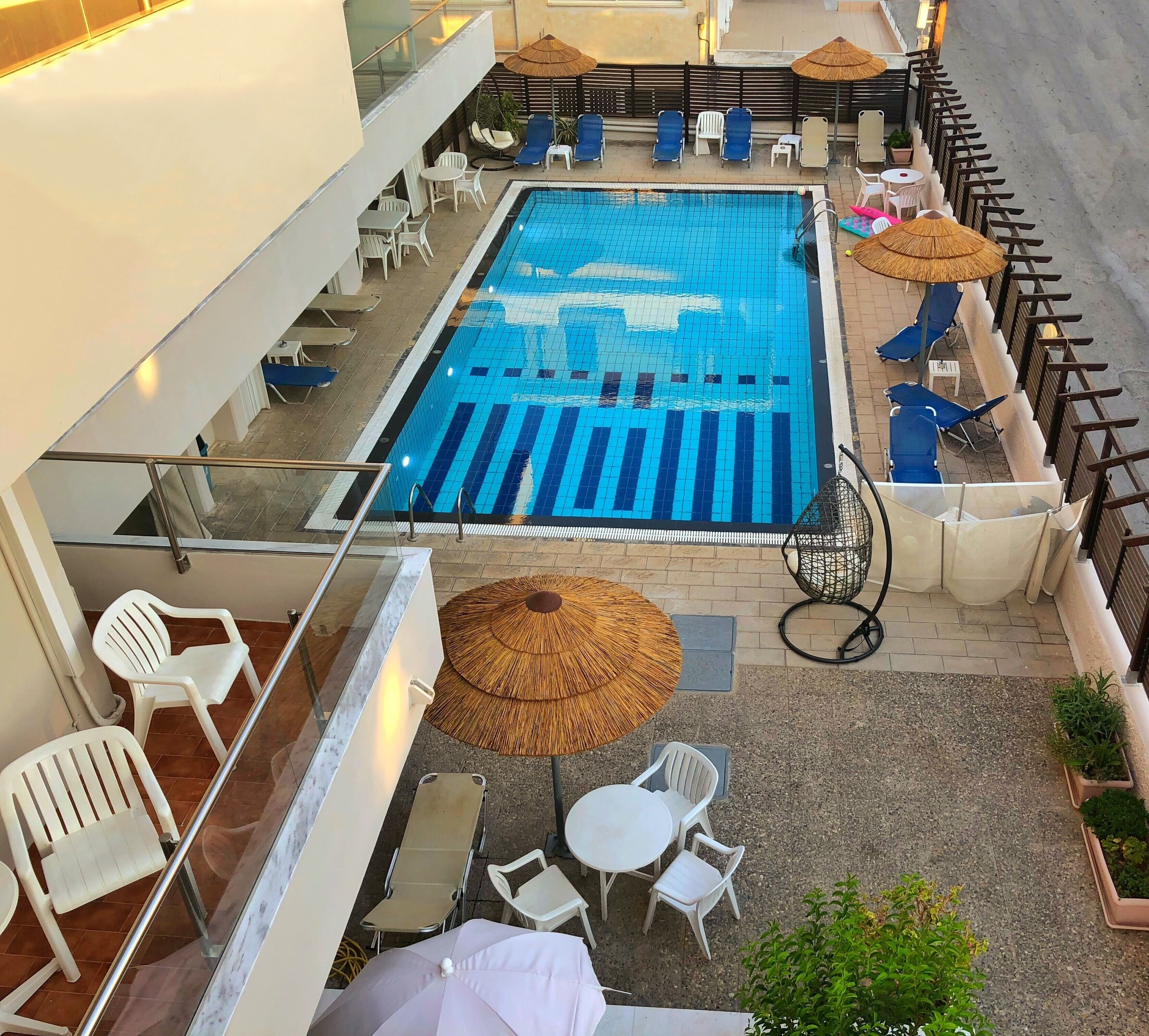 A rooftop pool area with lounge chairs, umbrellas, and a glass balustrade.