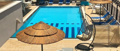 حمّام سباحة خارجي، مظلات على حمّام السباحة، مقاعد للتشمس