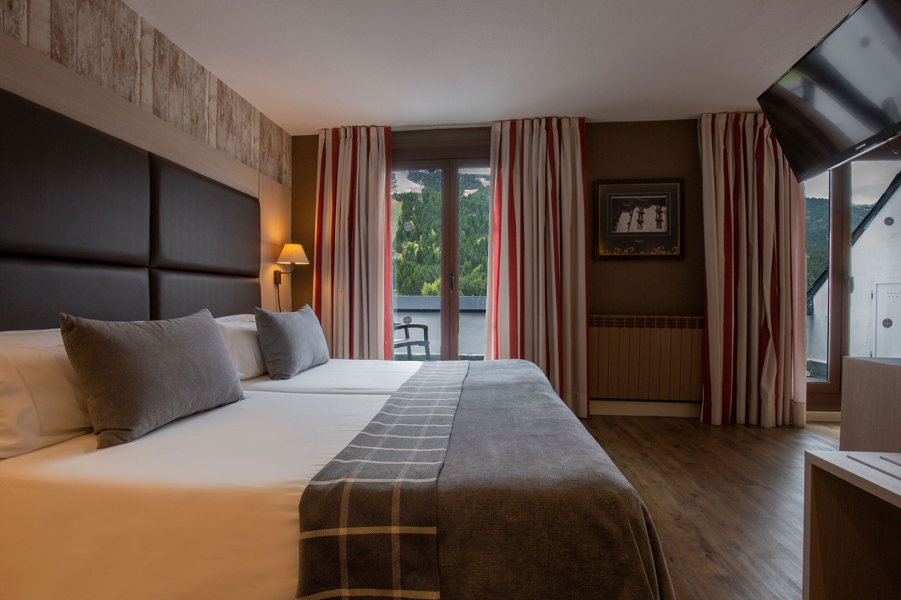 Une chambre d’hôtel avec un grand lit, une tête de lit, un téléviseur et une vue sur l’extérieur.