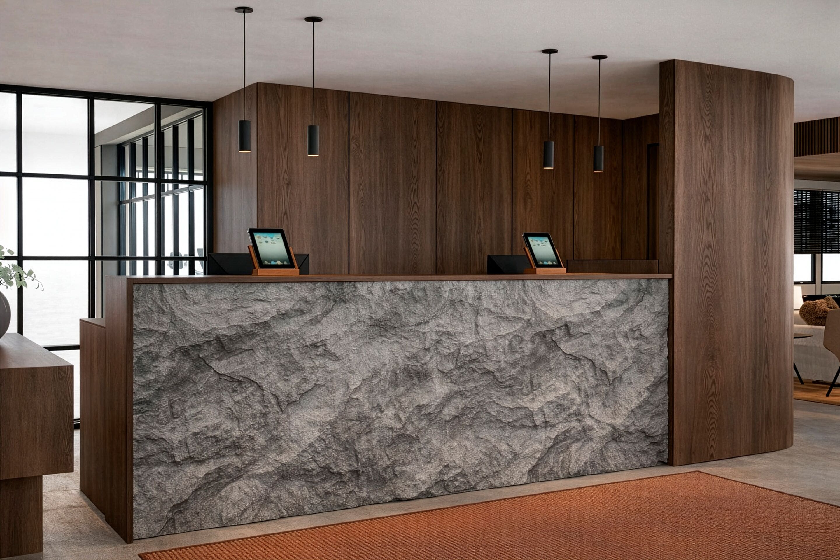 A reception desk with two computer monitors, wooden paneling, and pendant lighting.