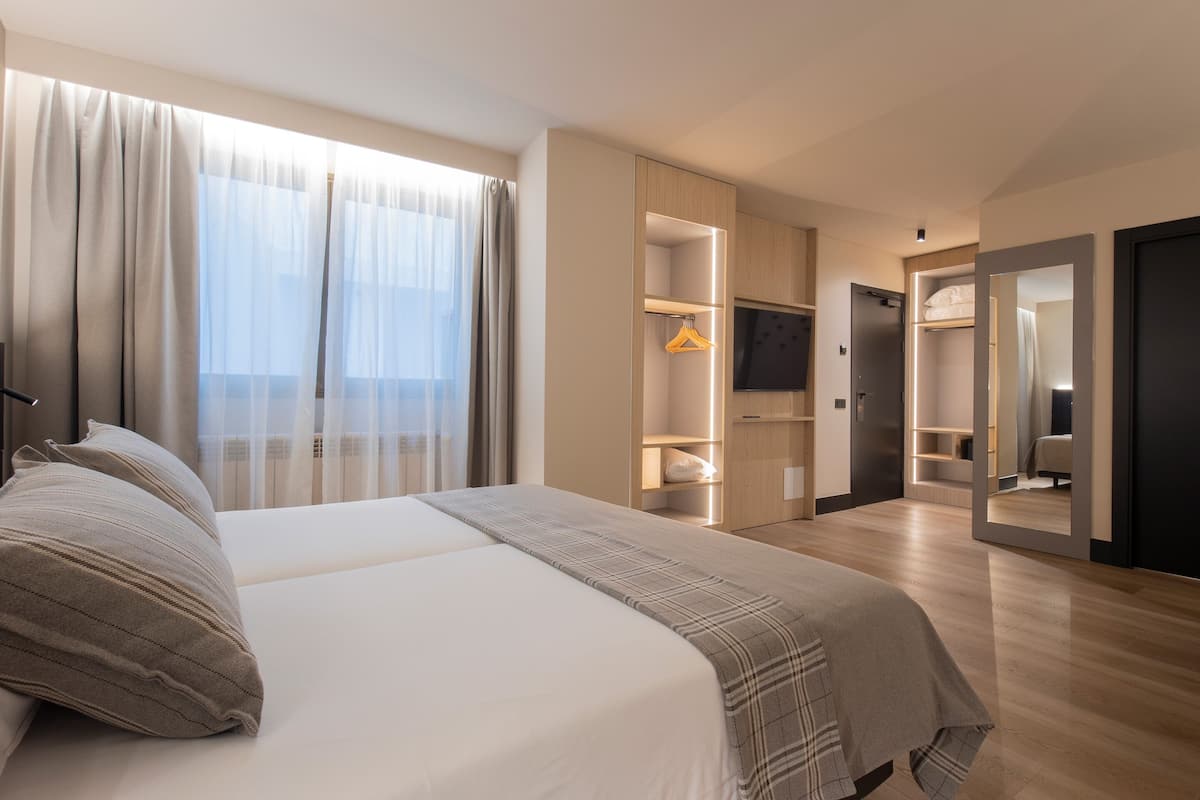 A modern hotel room with a large bed, a walk-in closet, a television, and a mirror.