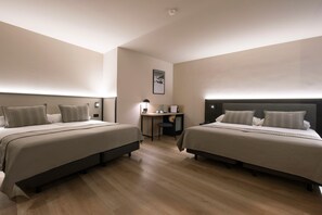 Habitación de hotel con dos camas, un escritorio y una silla.