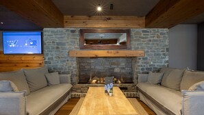 A cozy living room with a stone fireplace, a wooden coffee table, and two grey sofas.