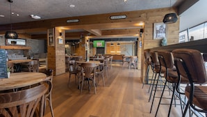 A restaurant with wooden floors, tables, and chairs. There are signs indicating separate areas for men and women.