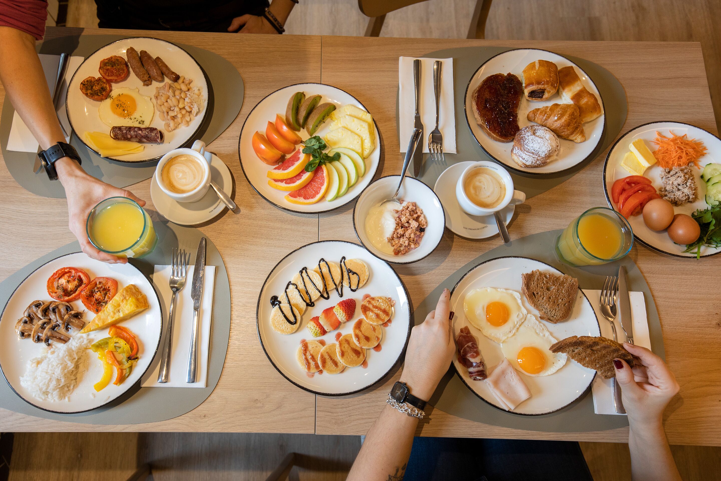 A breakfast buffet with various dishes including eggs, sausages, and fruits.